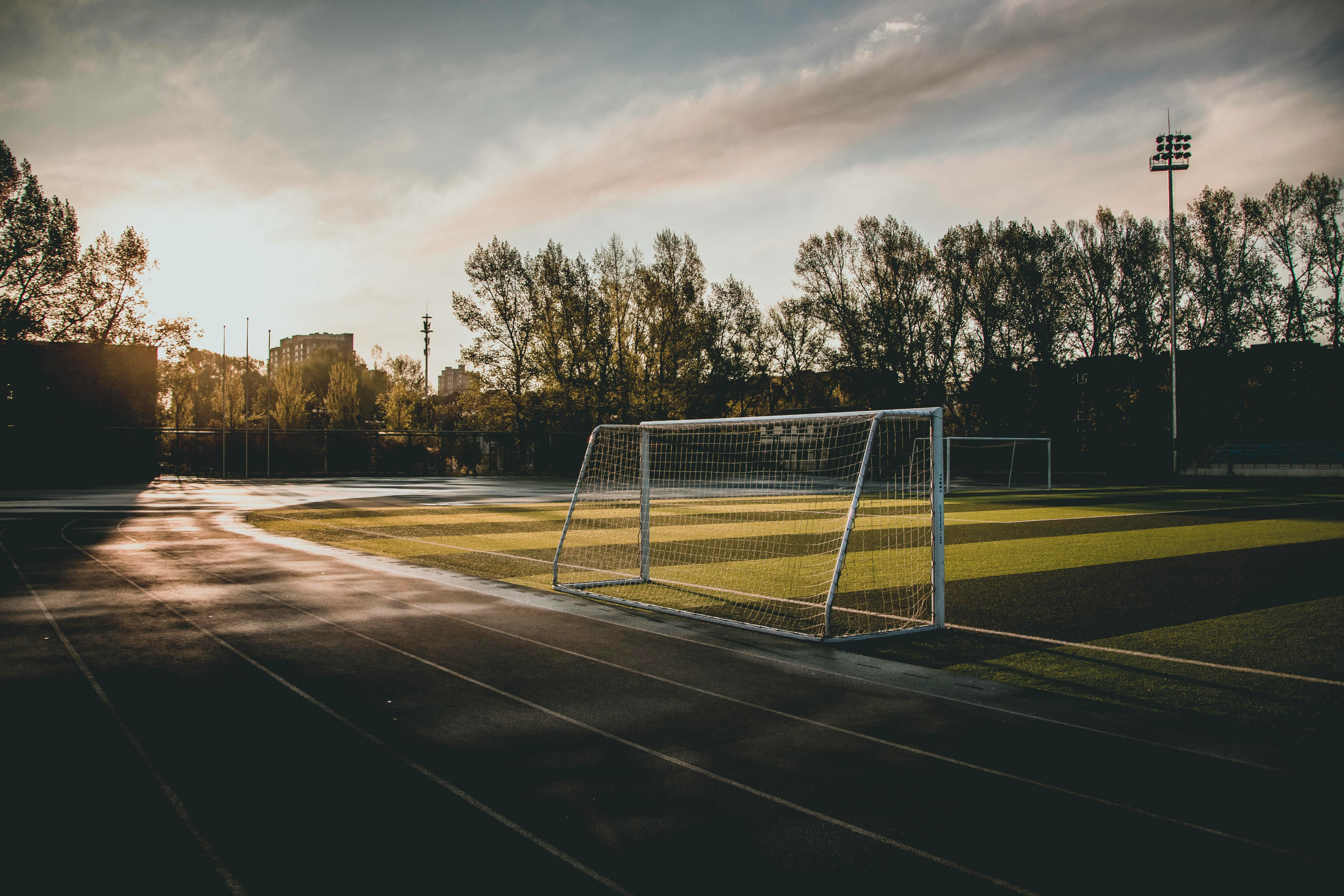 Empty soccer goal on an outdoor field at sunset with trees in the background